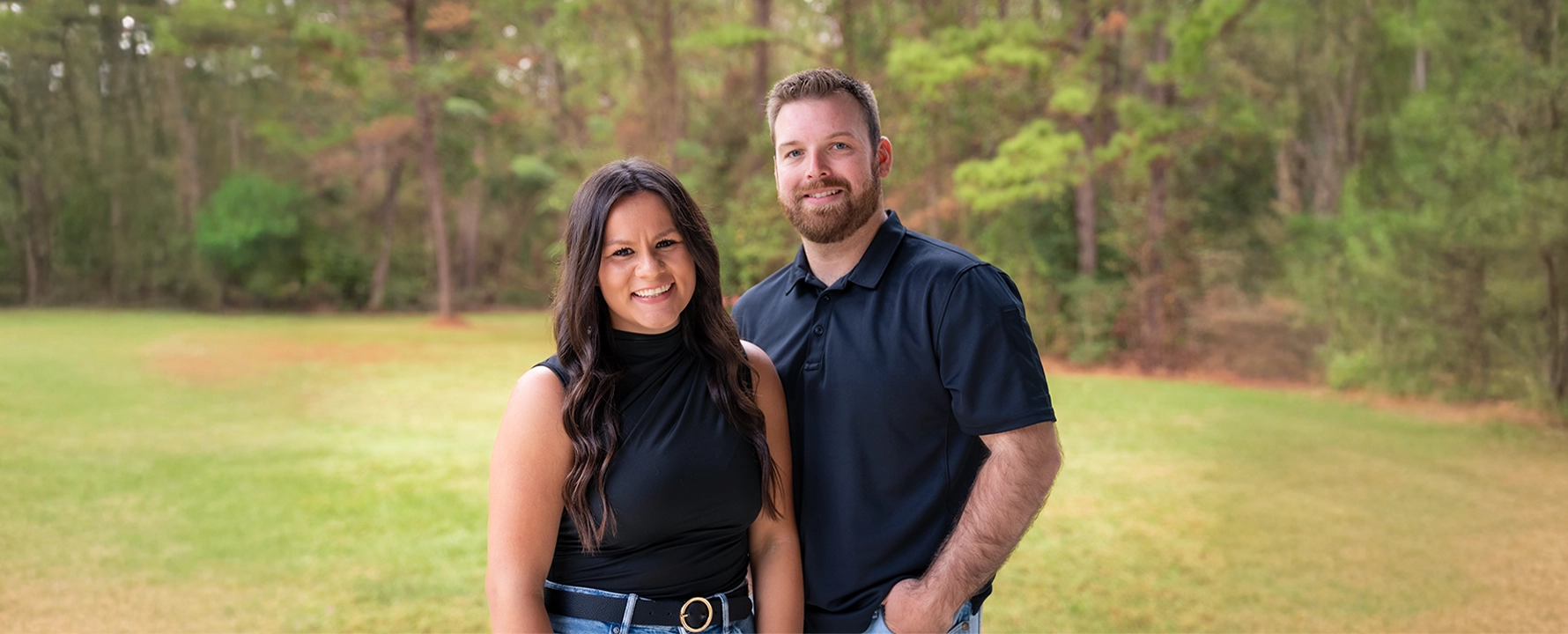 Portrait of the company founders standing outdoors together, smiling, representing the leadership team behind the brand.
