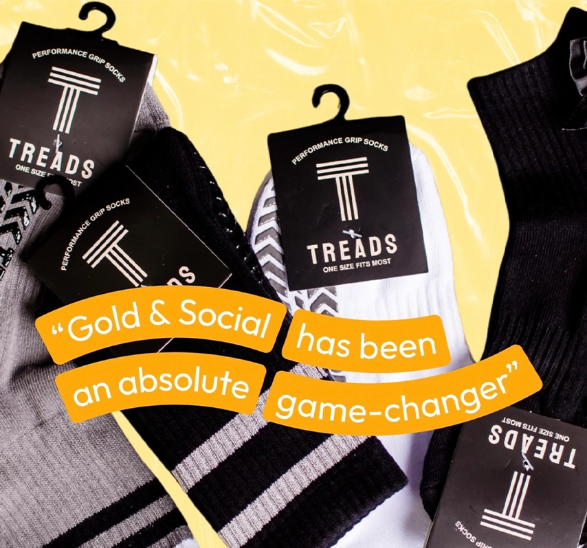 Flat lay of performance grip socks packaging labeled Treads with a testimonial quote reading “Gold & Social has been an absolute game-changer,” promoting athletic apparel and digital marketing success.